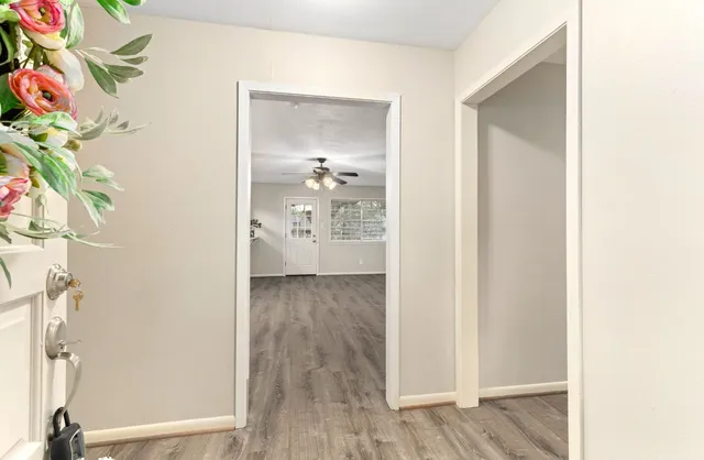 a view of a hallway with wooden floor and a bathroom