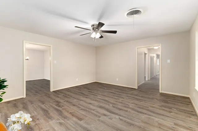 an empty room with wooden floor and ceiling fan