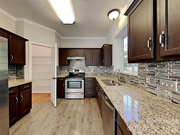 a kitchen with stainless steel appliances granite countertop wooden cabinets a stove top oven a sink and dishwasher