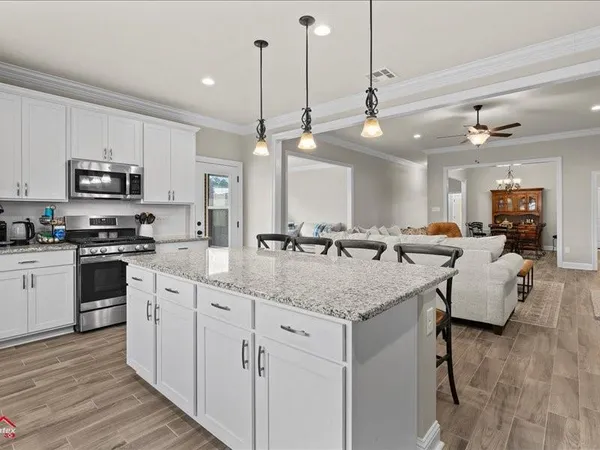 a kitchen with stainless steel appliances granite countertop a sink a stove and a wooden floors