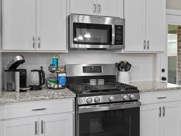a kitchen with stainless steel appliances granite countertop white cabinets and a stove top oven with granite countertops