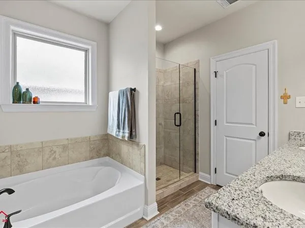 a bathroom with a granite countertop tub sink and mirror