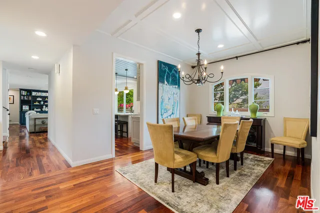 a dining room with wooden floor a chandelier a wooden table and chairs