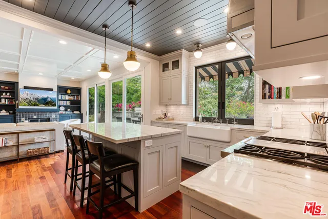 a kitchen with a stove a sink dishwasher a dining table and chairs with wooden floor