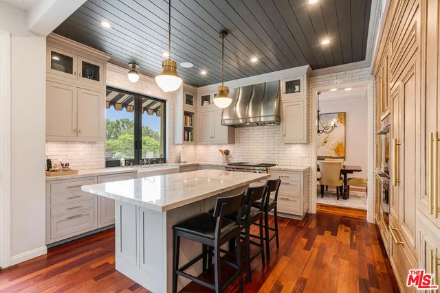 a kitchen with stainless steel appliances granite countertop a stove a sink dishwasher and a refrigerator with wooden floor