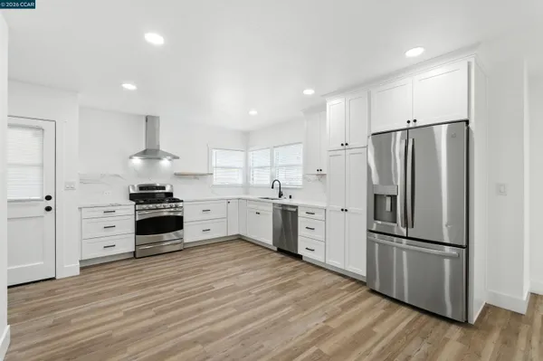 a kitchen with stainless steel appliances a refrigerator sink and wooden floor