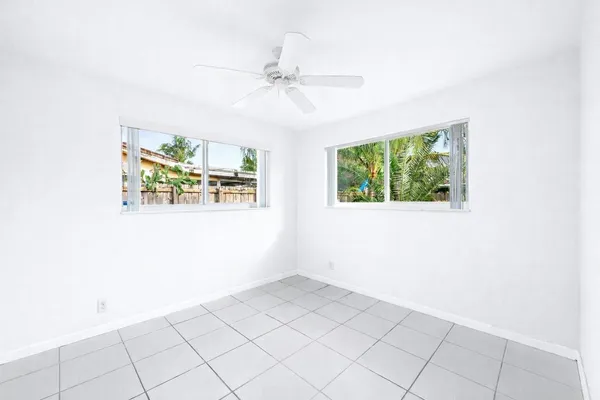 an empty room with windows and fan