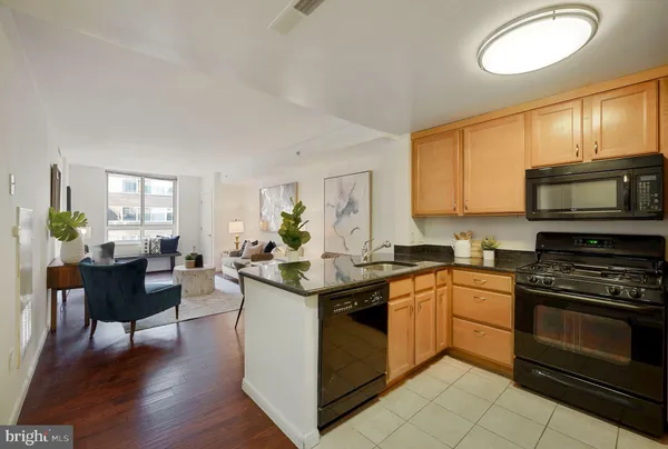 a kitchen with stainless steel appliances granite countertop a stove top oven a sink dishwasher a dining table and chairs with wooden floor