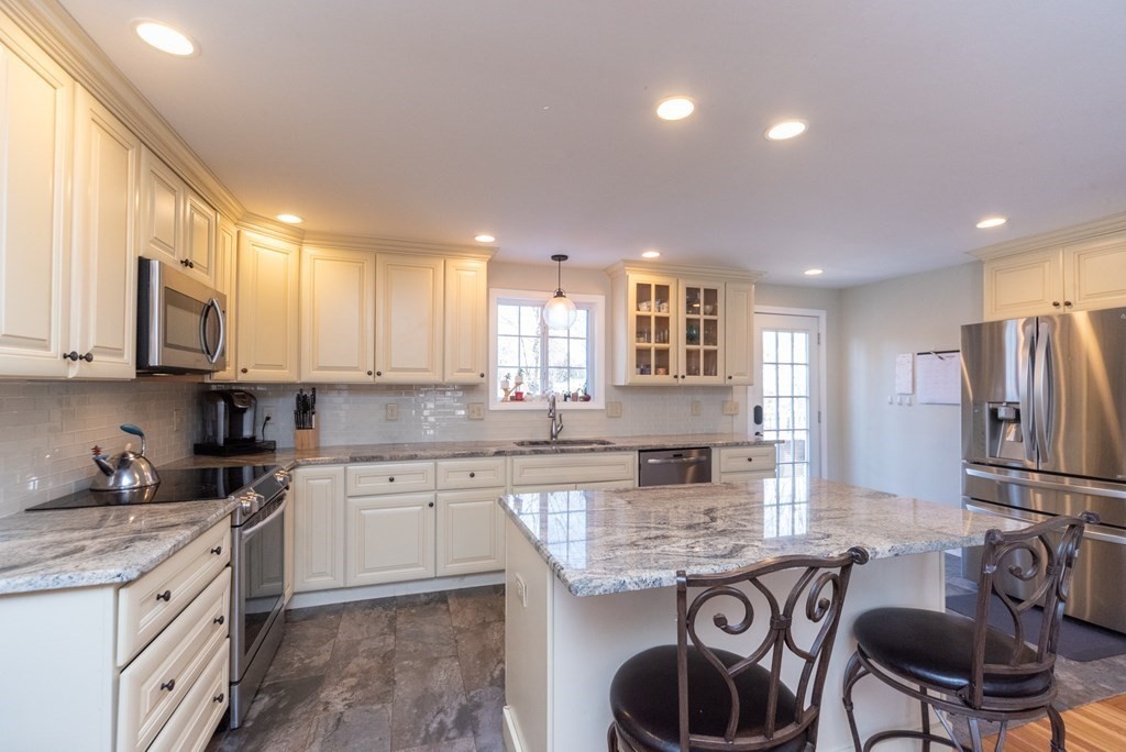 112 Elmwood Street Auburn, MA 01501 - Photo 8 of 40 a kitchen with kitchen island granite countertop a stove a sink a refrigerator and cabinets