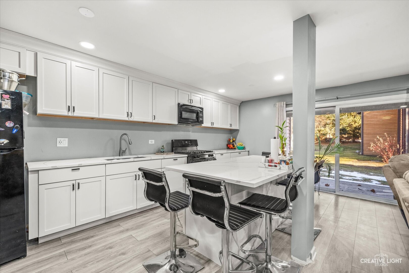 950 Jefferson Avenue, Unit B Elgin, IL 60120 - Photo 5 of 10 a kitchen with a sink stove and white cabinets with wooden floor