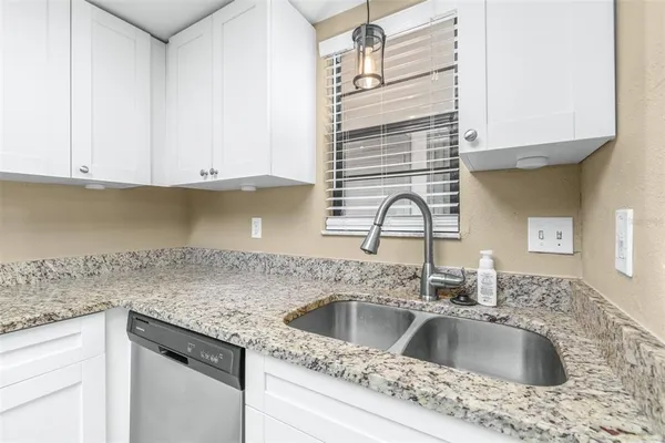 a kitchen with granite countertop a sink and refrigerator