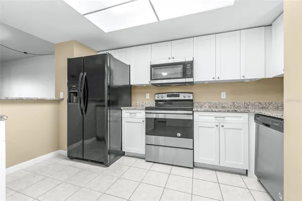a kitchen with granite countertop white cabinets and stainless steel appliances