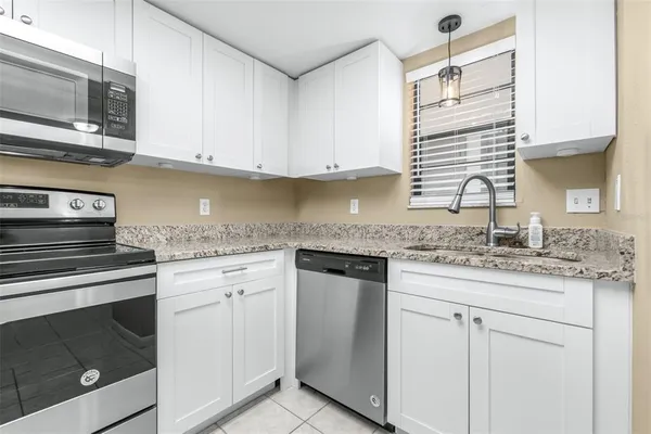 a kitchen with granite countertop white cabinets stainless steel appliances and a sink