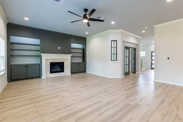 a view of an empty room with a fireplace and a ceiling fan