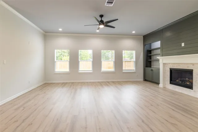 an empty room with wooden floor fireplace and windows