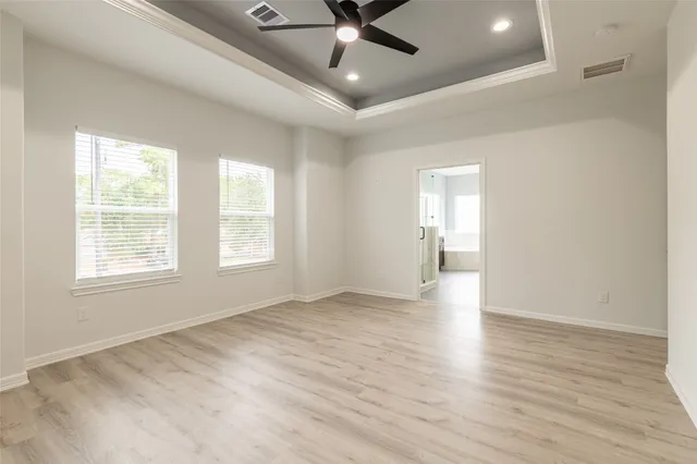 an empty room with wooden floor chandelier fan and windows