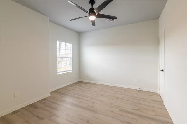an empty room with a window and a ceiling fan