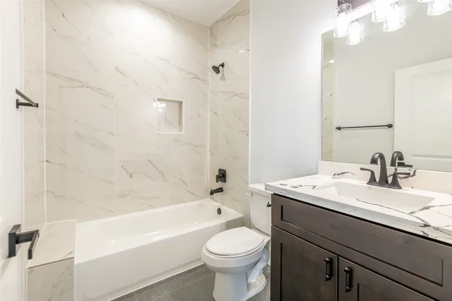 a bathroom with a granite countertop toilet a sink a mirror a bathtub and shower