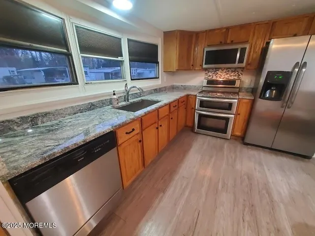 a view of kitchen and empty room with wooden floor