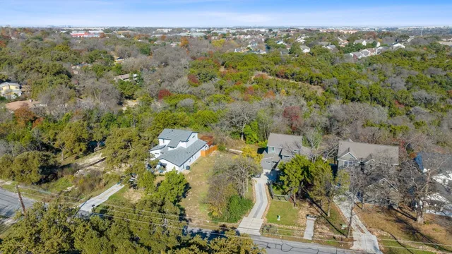 an aerial view of a residential houses with outdoor space and trees