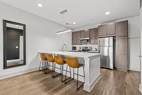 a kitchen with stainless steel appliances granite countertop a refrigerator a sink dishwasher a stove with wooden cabinets and floor