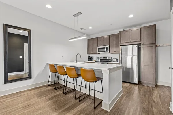 a kitchen with stainless steel appliances granite countertop a refrigerator a sink dishwasher a stove with wooden cabinets and floor