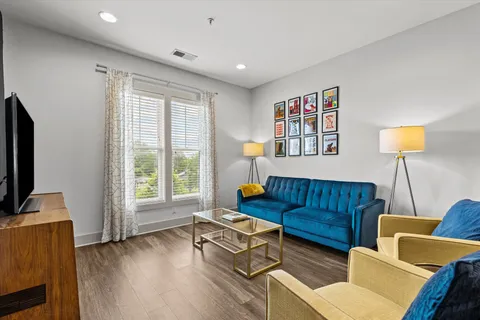 a living room with furniture a flat screen tv and a window