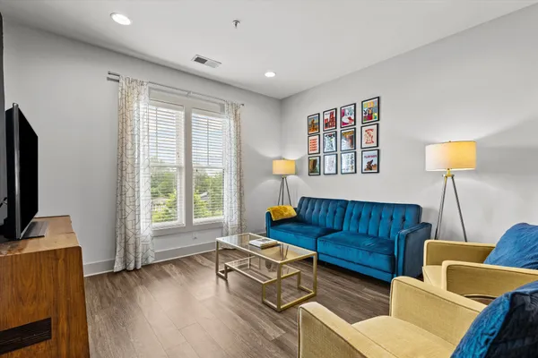 a living room with furniture a flat screen tv and a window