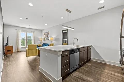 a view of living room with stainless steel appliances granite countertop furniture and a wooden floor