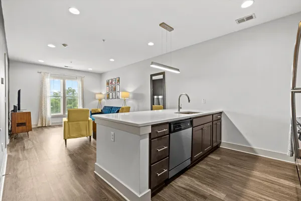 a view of living room with stainless steel appliances granite countertop furniture and a wooden floor