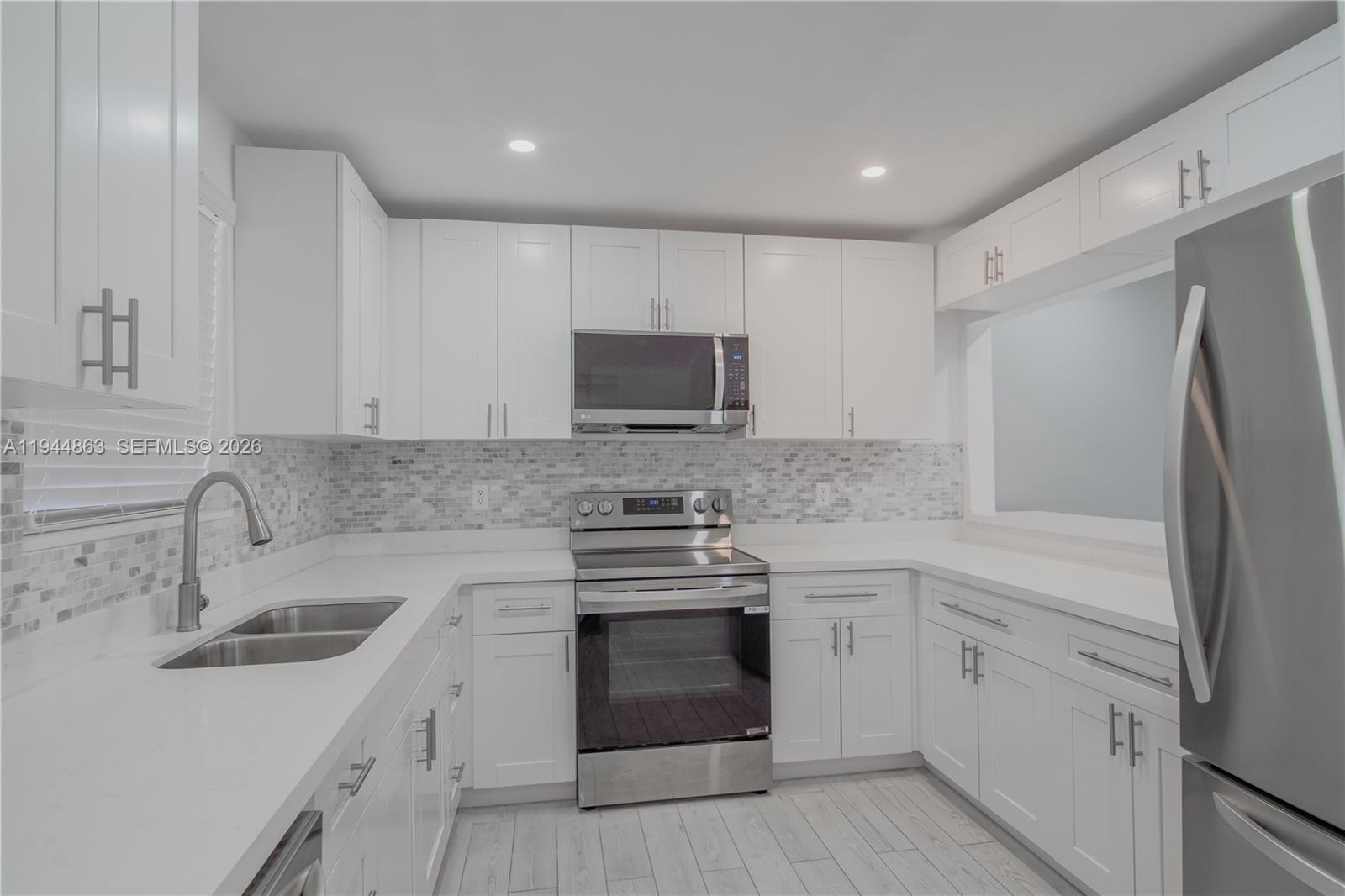 2830 Riverside Drive, Unit 2013 Coral Springs, FL 33065 - Photo 2 of 14 a kitchen with white cabinets stainless steel appliances and sink
