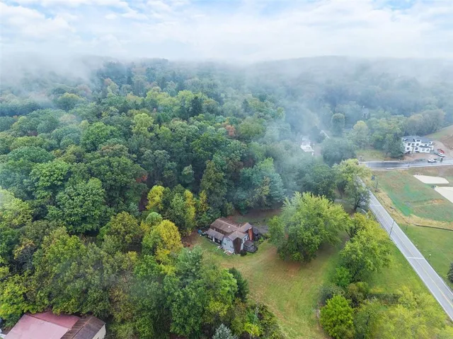 an aerial view of residential house with outdoor space and trees all around