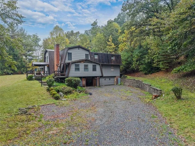 a view of a big house with a big yard plants and large trees