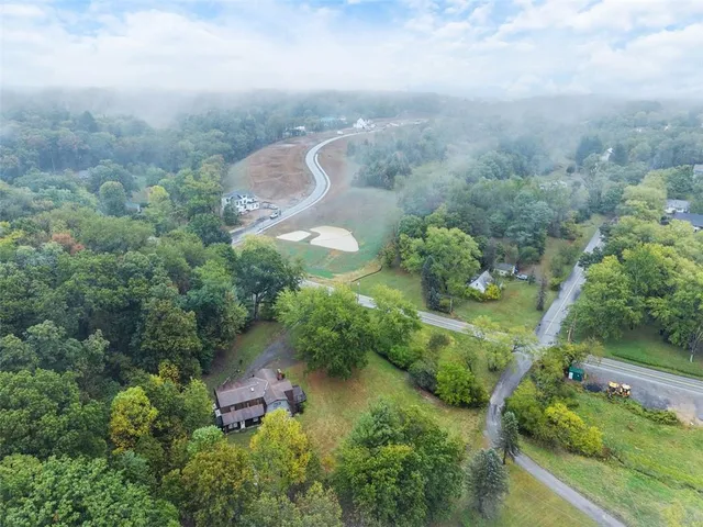 an aerial view of residential house with outdoor space and trees all around