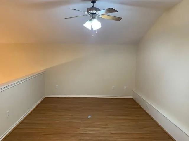 a view of a room with wooden floor and a ceiling fan