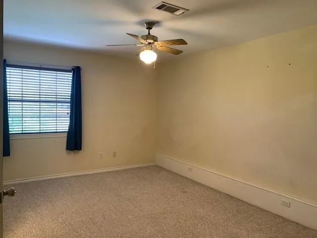 an empty room with windows and fan