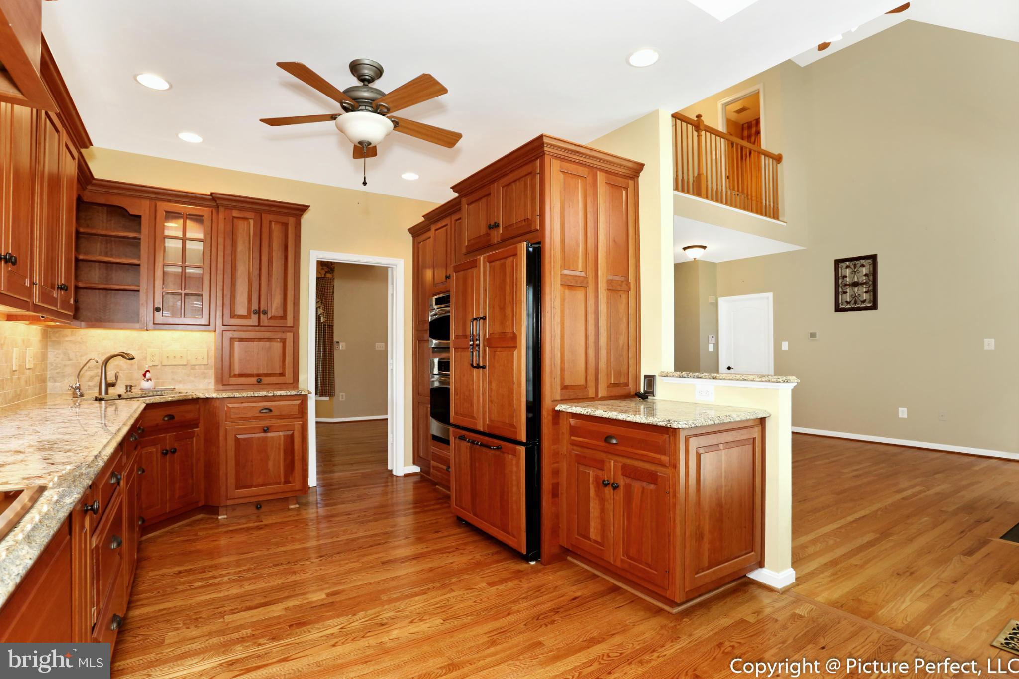 2557 Bear Den Road Frederick, MD 21701 - Photo 5 of 30 a kitchen with stainless steel appliances granite countertop a refrigerator a sink dishwasher and a stove top oven with wooden floor