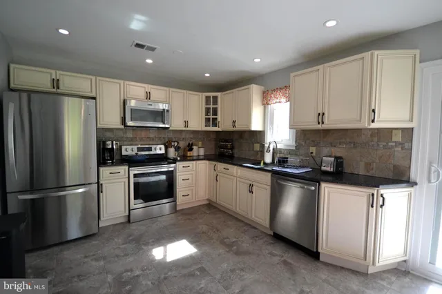 a kitchen with granite countertop a refrigerator stove and microwave