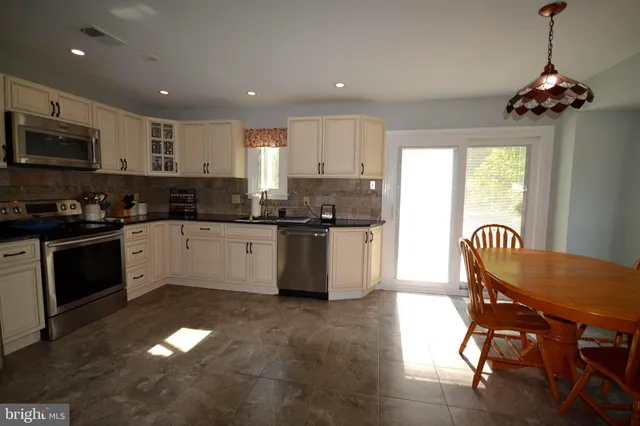 a kitchen with stainless steel appliances granite countertop a stove a sink a microwave a refrigerator and cabinets