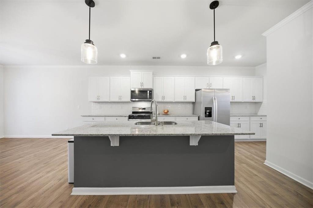 7946 Hansell Court Lithia Springs, GA 30122 - Photo 12 of 58 a kitchen with stainless steel appliances granite countertop a sink a stove a refrigerator and island with wooden floor