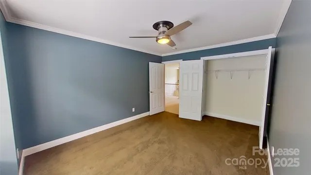 an empty room with a ceiling fan and carpet