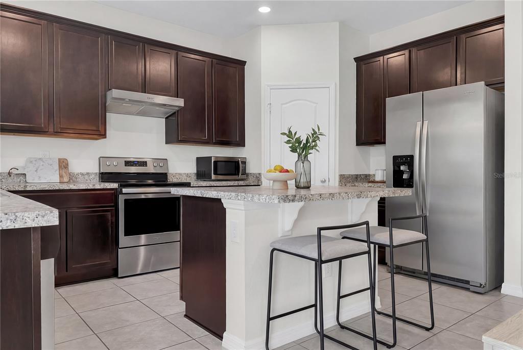 4548 Orchard Grove Road St. Cloud, FL 34772 - Photo 4 of 18 a kitchen with stainless steel appliances granite countertop a refrigerator a stove a sink and a microwave