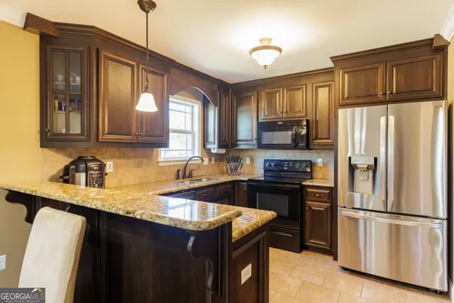 a kitchen with granite countertop a refrigerator stove top oven and sink