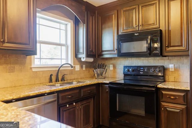 a kitchen with granite countertop a sink cabinets stainless steel appliances and a window