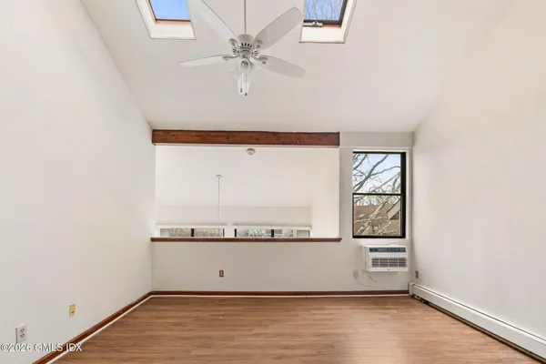 an empty room with wooden floor and fan