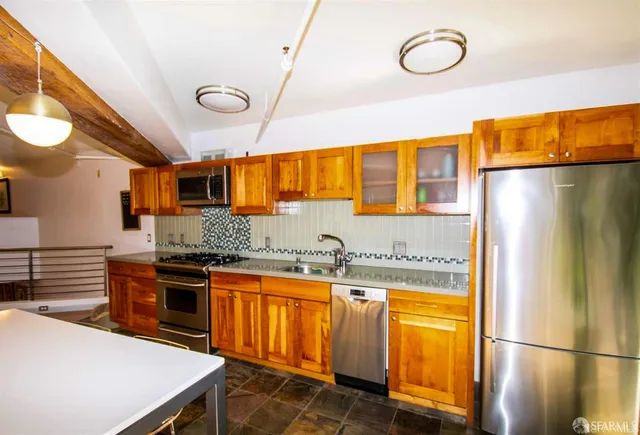 a kitchen with stainless steel appliances granite countertop a sink and a refrigerator