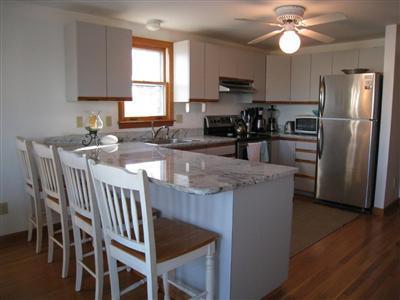 70 Meridian Way Barnstable, MA 02630 - Photo 6 of 29 a kitchen with stainless steel appliances granite countertop a sink a stove a refrigerator with a dining table and chairs