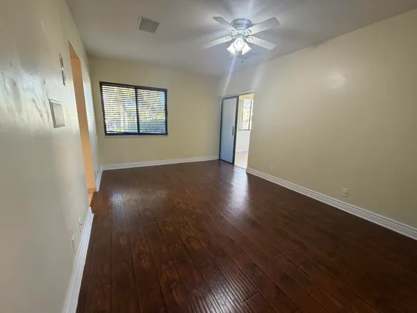 a view of an empty room with a window and wooden floor