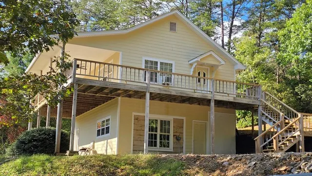 a view of a white house with large windows and a small yard