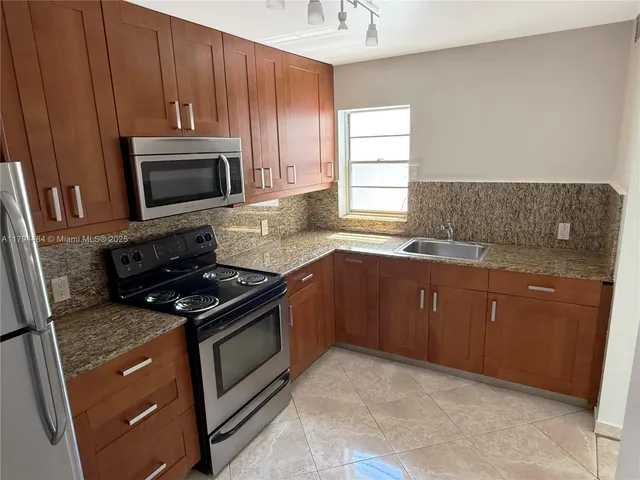 a kitchen with sink a microwave a stove and cabinets